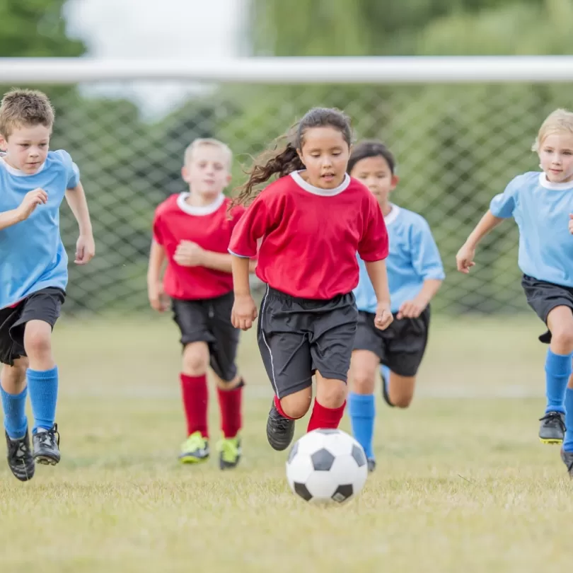 Youth soccer teams running down the field kicking ball