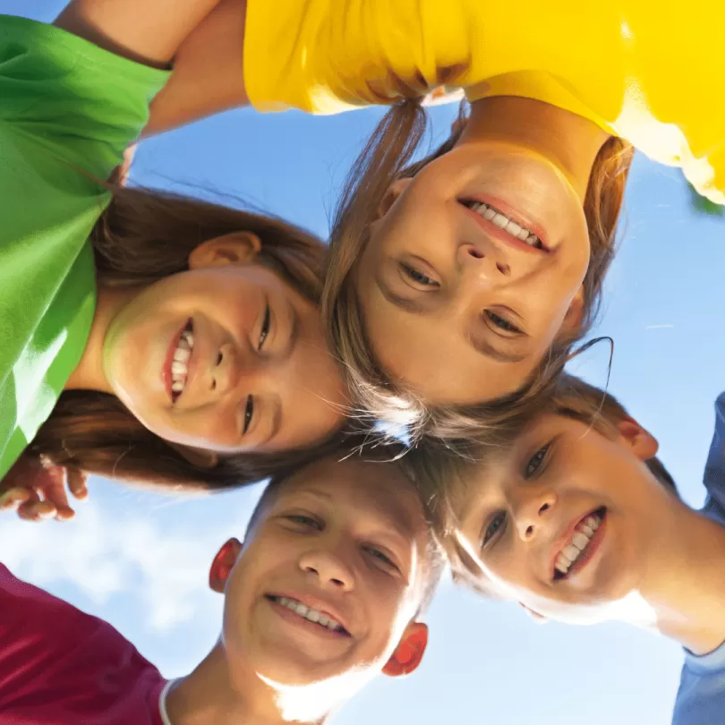 Kids smiling and huddling together.
