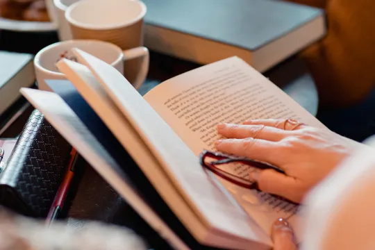 A closeup of someone holding a book during a book club meeting.