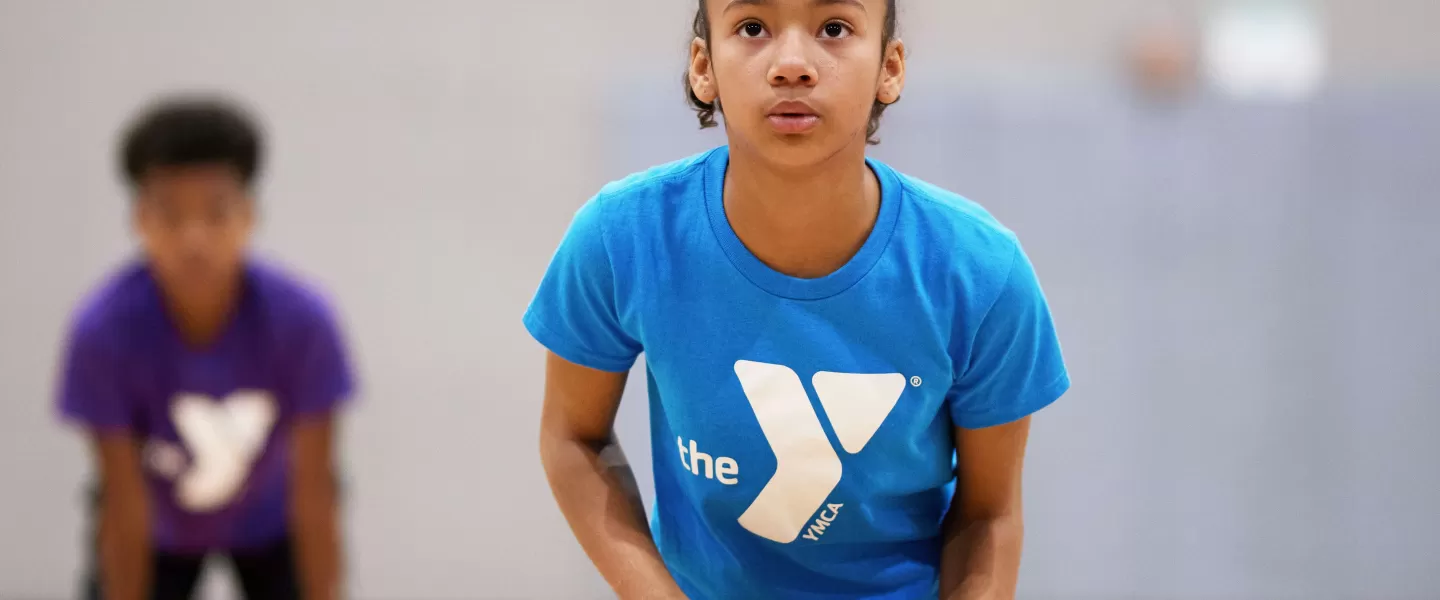 A girl wearing a blue shirt concentrates as she prepares to shoot a basketball.