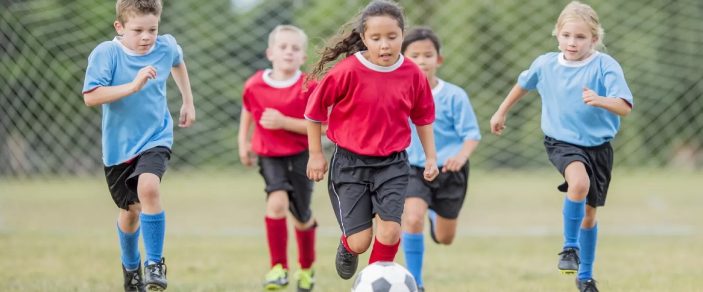 Youth soccer teams running down the field kicking ball