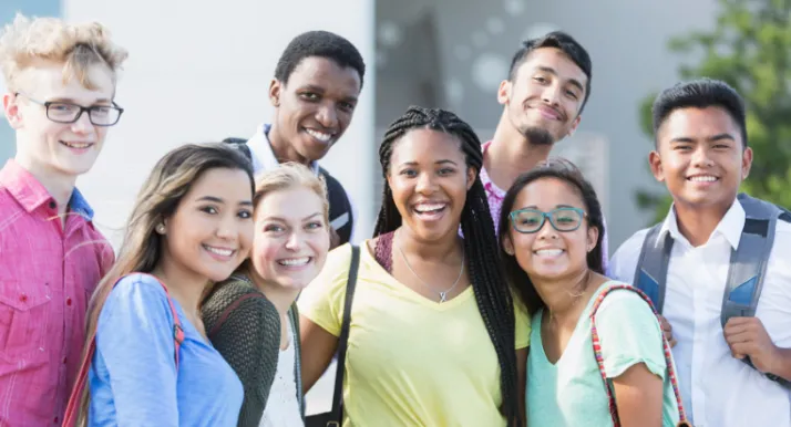 A group of teens smile at the camera at school.