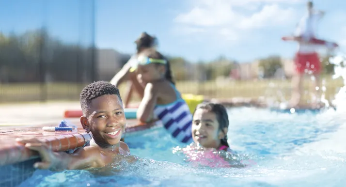 A boy smiles in a swimming pool.